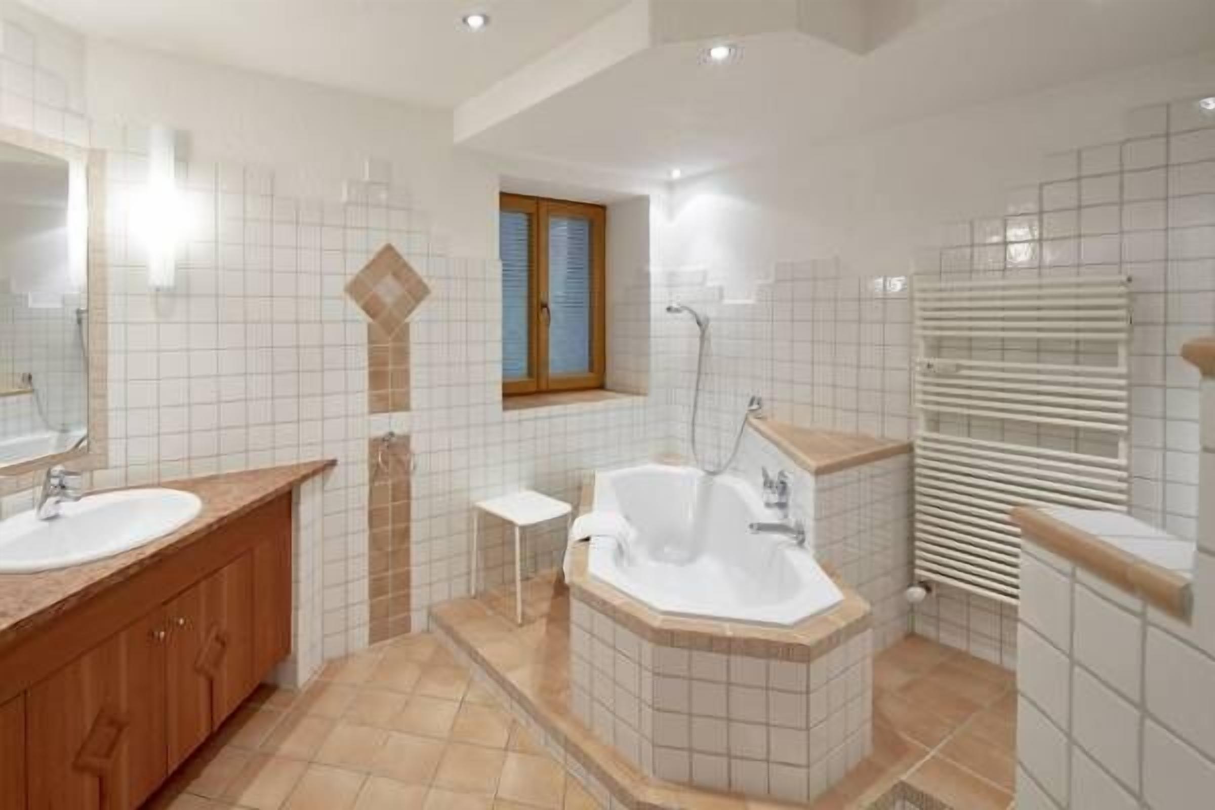 Un baño moderno con dos lavamanos, una bañera y una ducha.