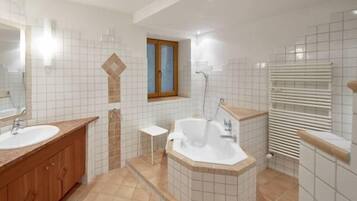 Un baño moderno con dos lavamanos, una bañera y una ducha.