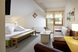 A cozy room with a bed, a bench, a sofa, a small table with a vase, and a lamp. - Gasthof Salzstadl (Reutte)