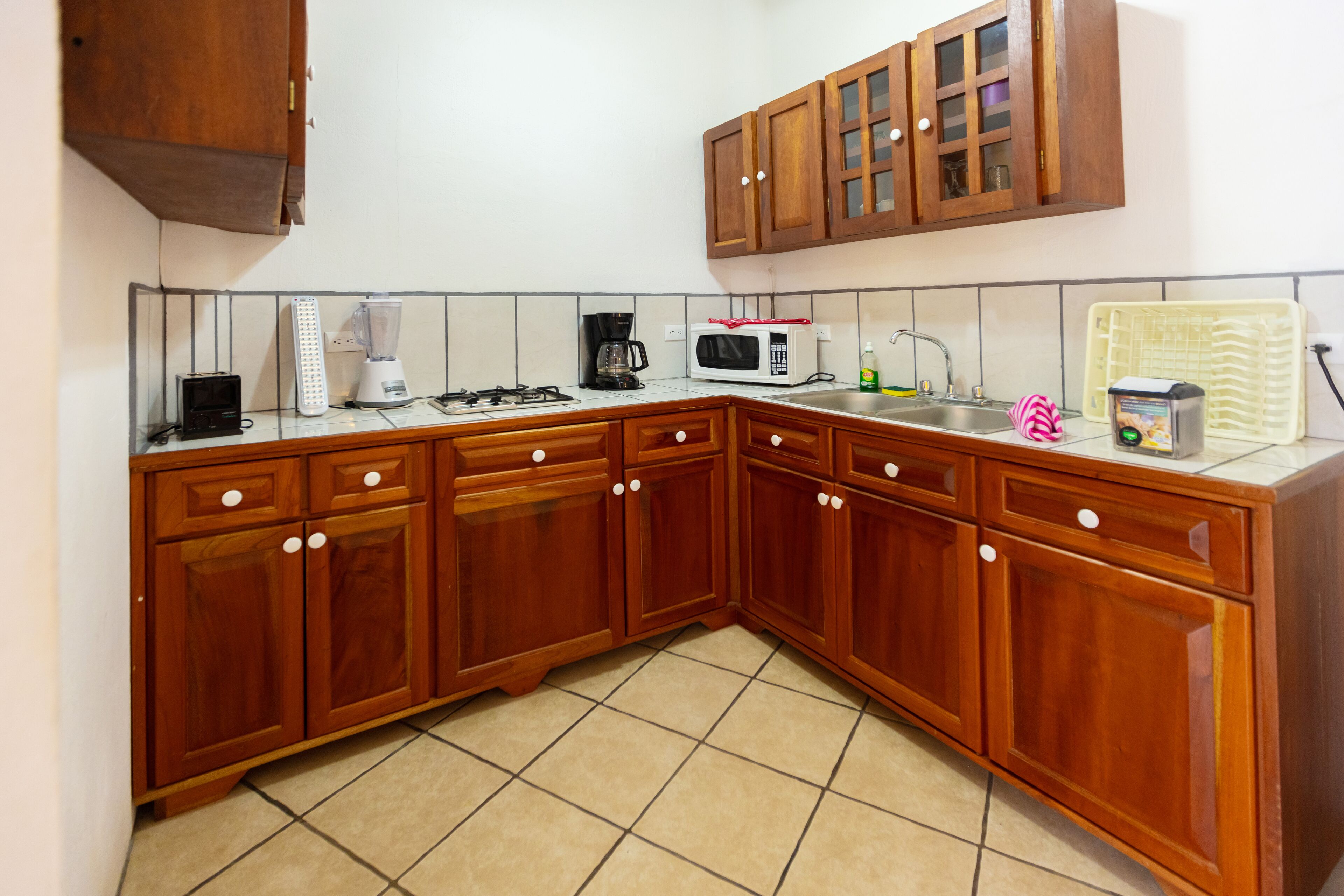 A kitchen with wooden cabinets, a microwave, a coffee maker, and a blender.