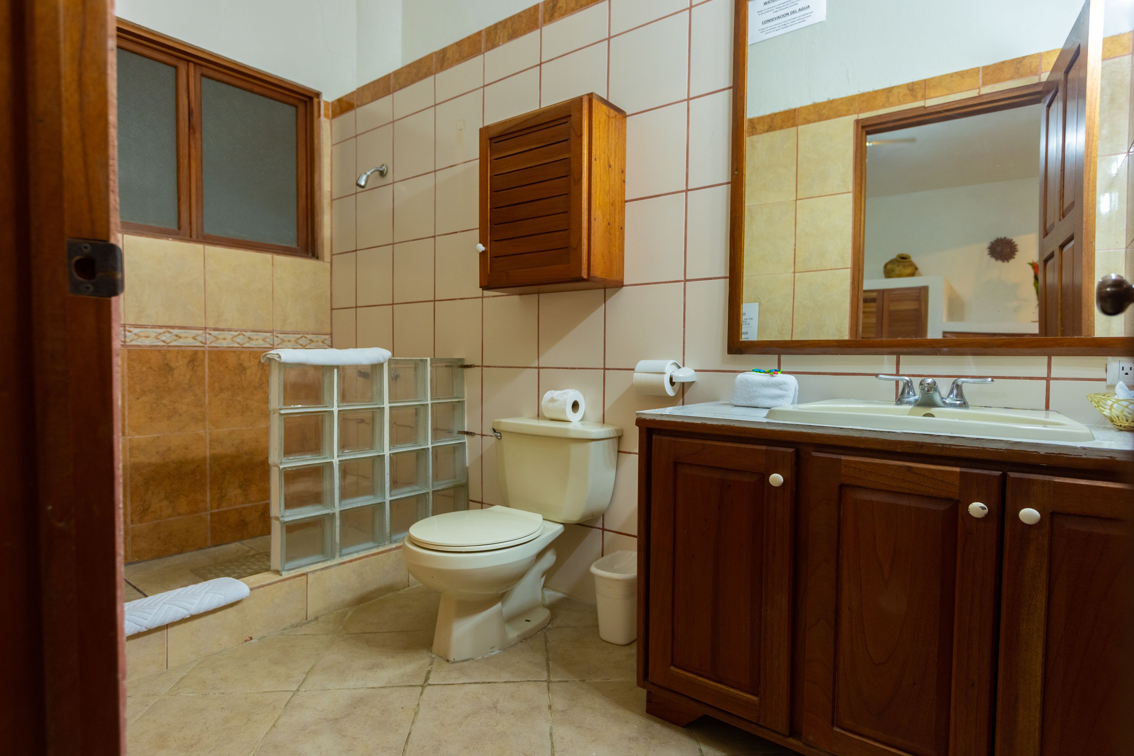 Ein Badezimmer mit Toilette, Waschbecken, Spiegel und Holzschränken.