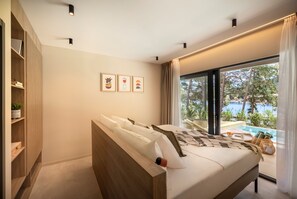 Une chambre moderne dotée d’un grand lit, d’une armoire intégrée et donnant sur une piscine extérieure.