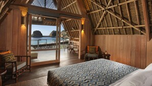 Een kamer met een groot bed, houten wanden en uitzicht op zee.