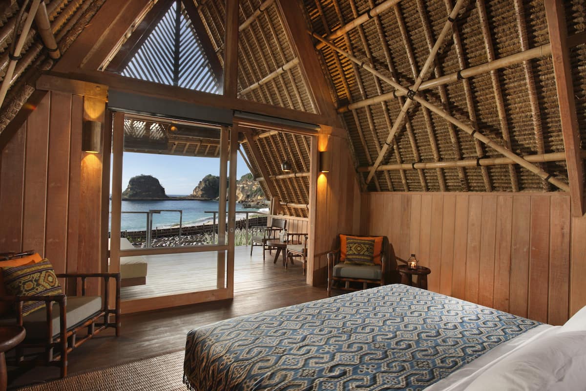 A room with a large bed, wooden walls, and a view of the sea.