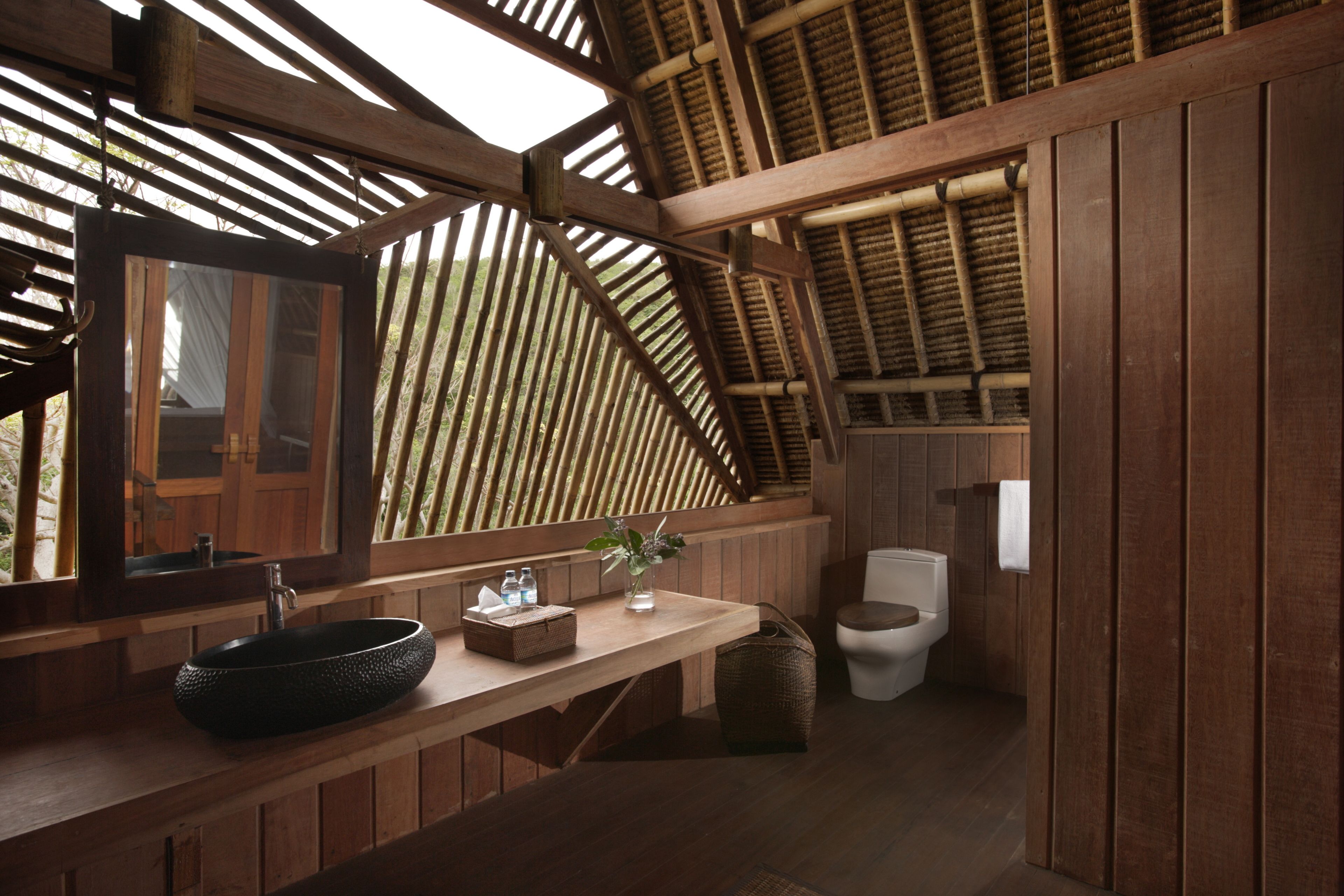Une salle de bain en bois avec un grand miroir, un lavabo et des toilettes.