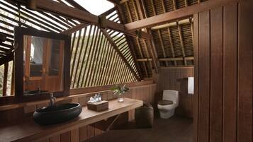 Une salle de bain en bois avec un grand miroir, un lavabo et des toilettes.