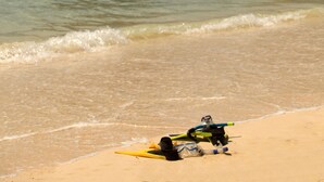 Een strand met helder turquoise water en twee grote rotsformaties op de achtergrond.