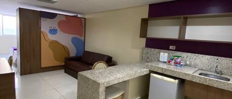 Una cocina compacta con isla integrada, un refrigerador y un lavamanos.
