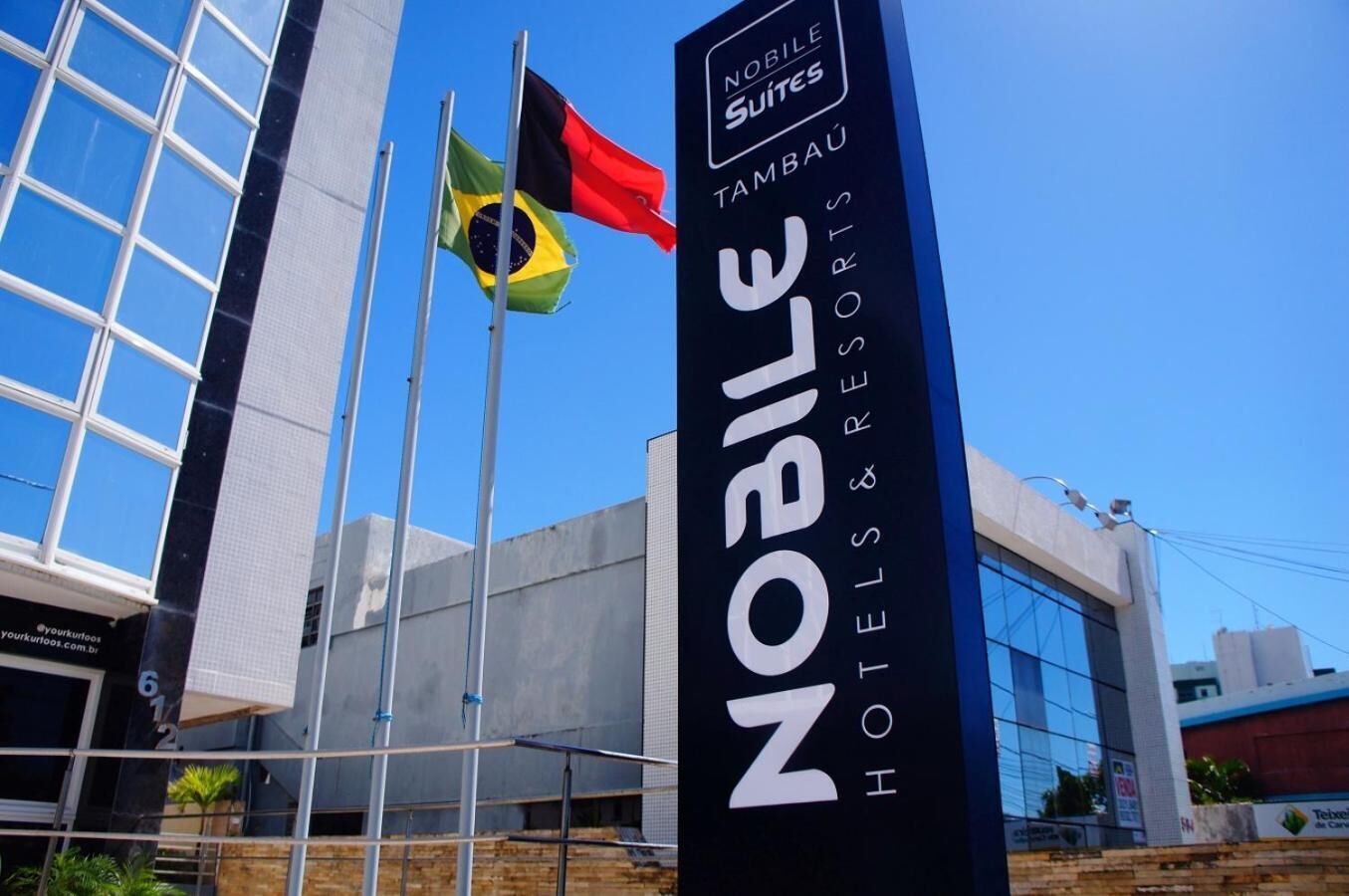 Placa de hotel com a inscrição 'NOBLE SUITES' e 'TAMBÁU HOTELS & RESORTS'.