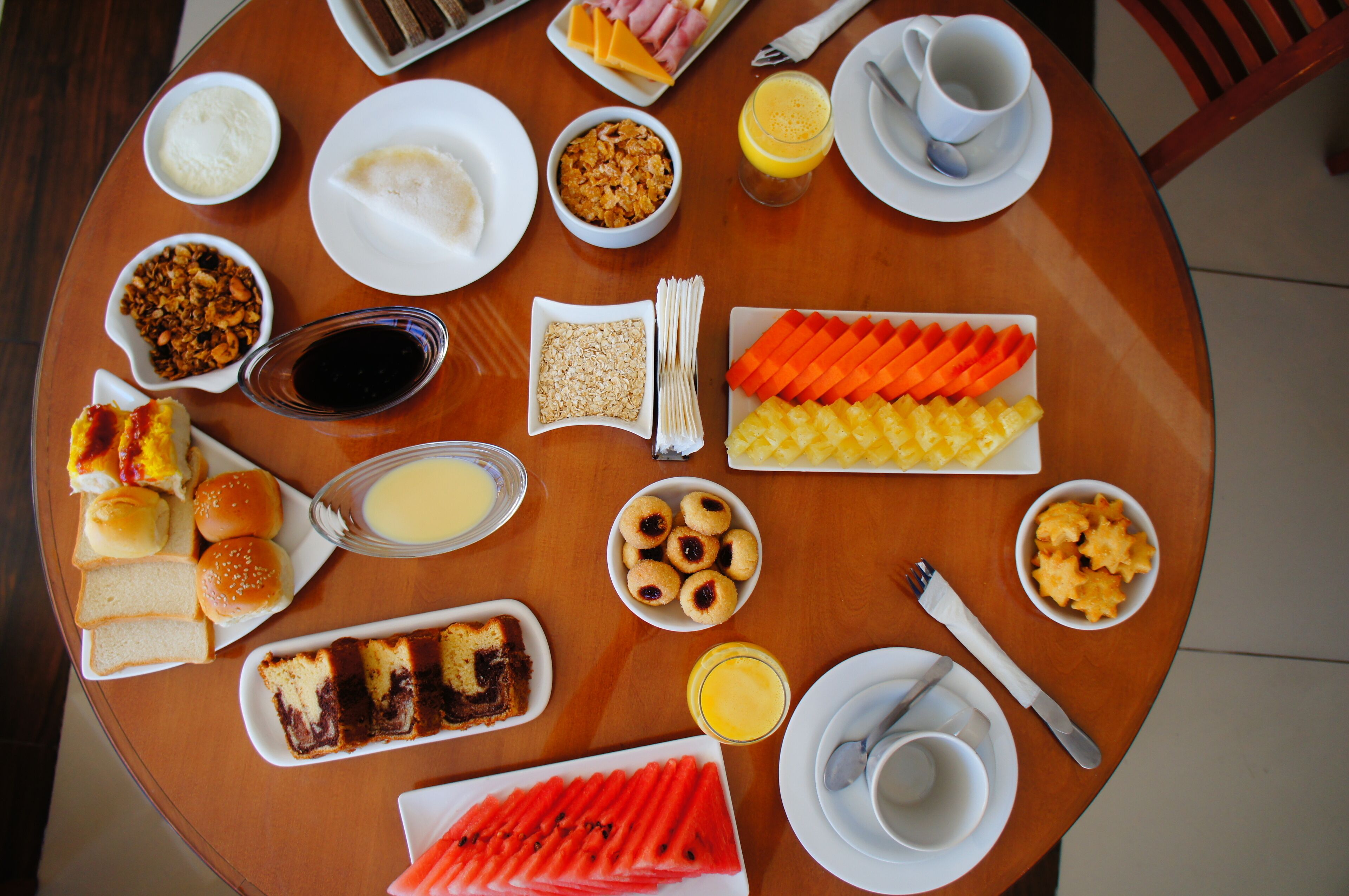 A table with various breakfast items including bread, pastries, and fruits.