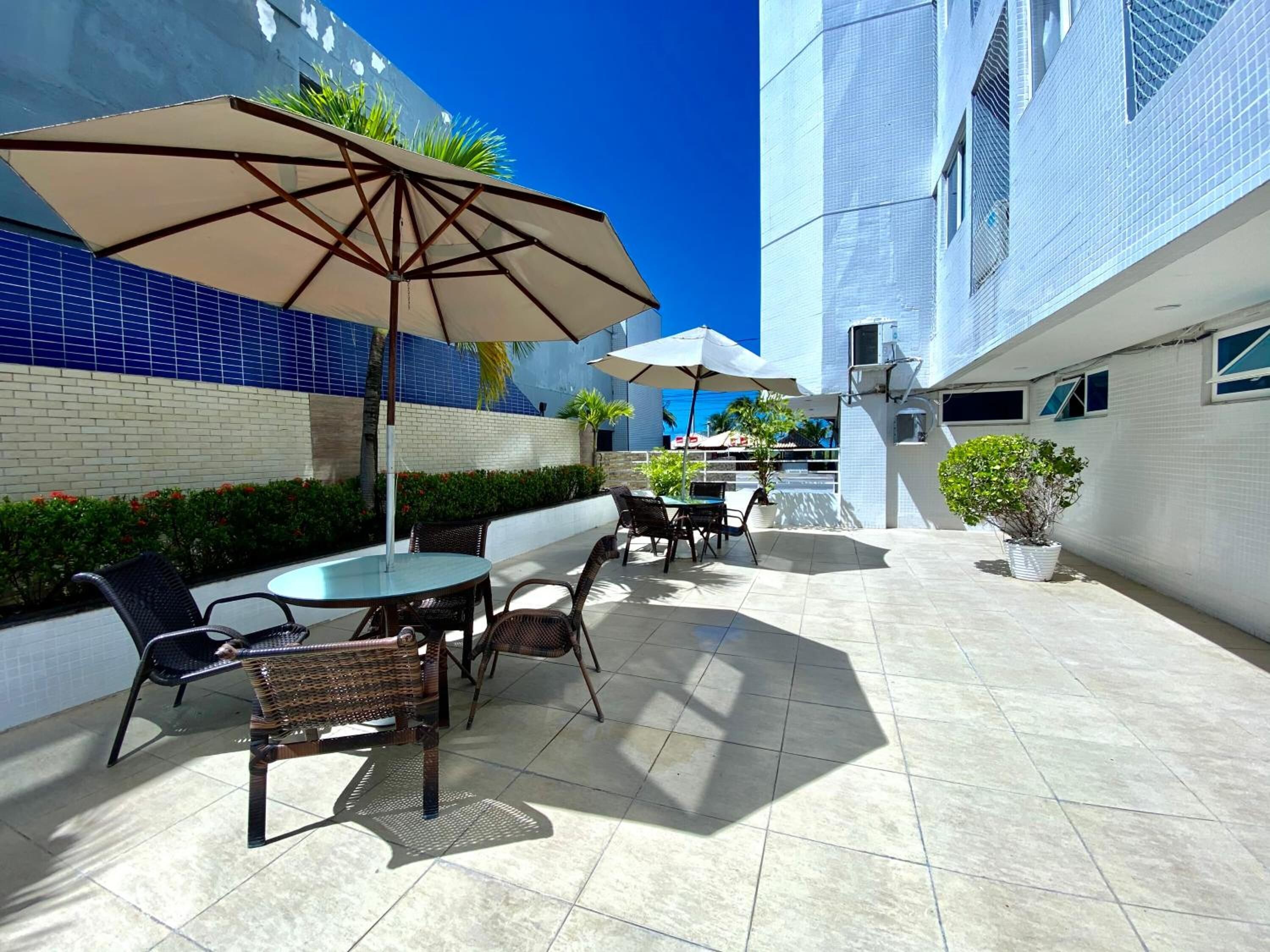 An outdoor patio area with tiled flooring, outdoor furniture, and umbrellas.