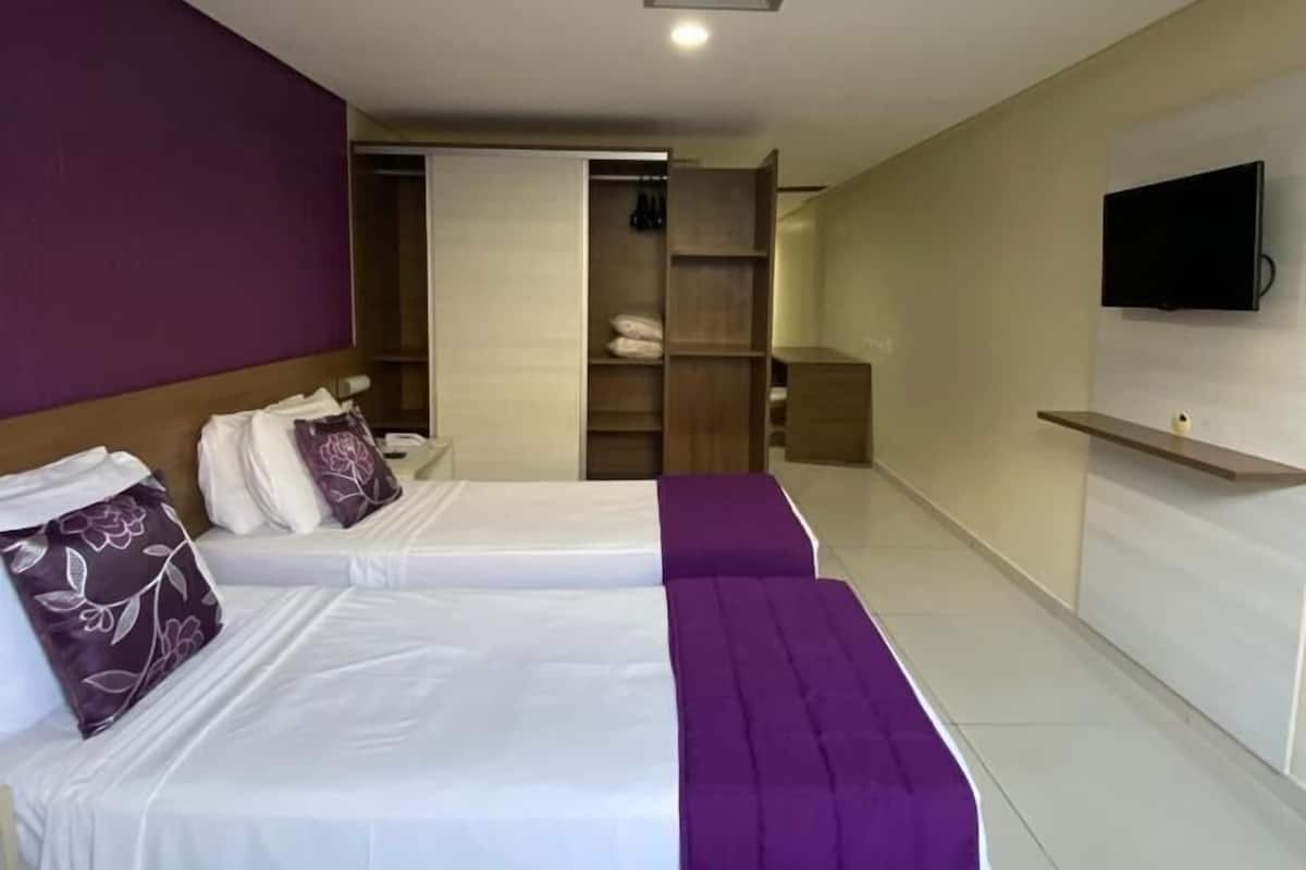 Hotellihuone, jossa on kaksi sänkyä, televisio ja vaatekaappi.
