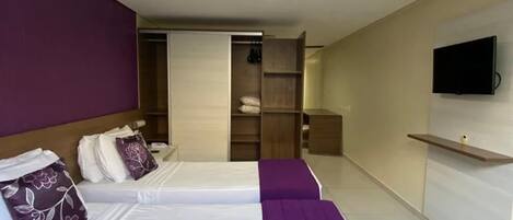 A hotel room with two beds, a television, and a wardrobe.