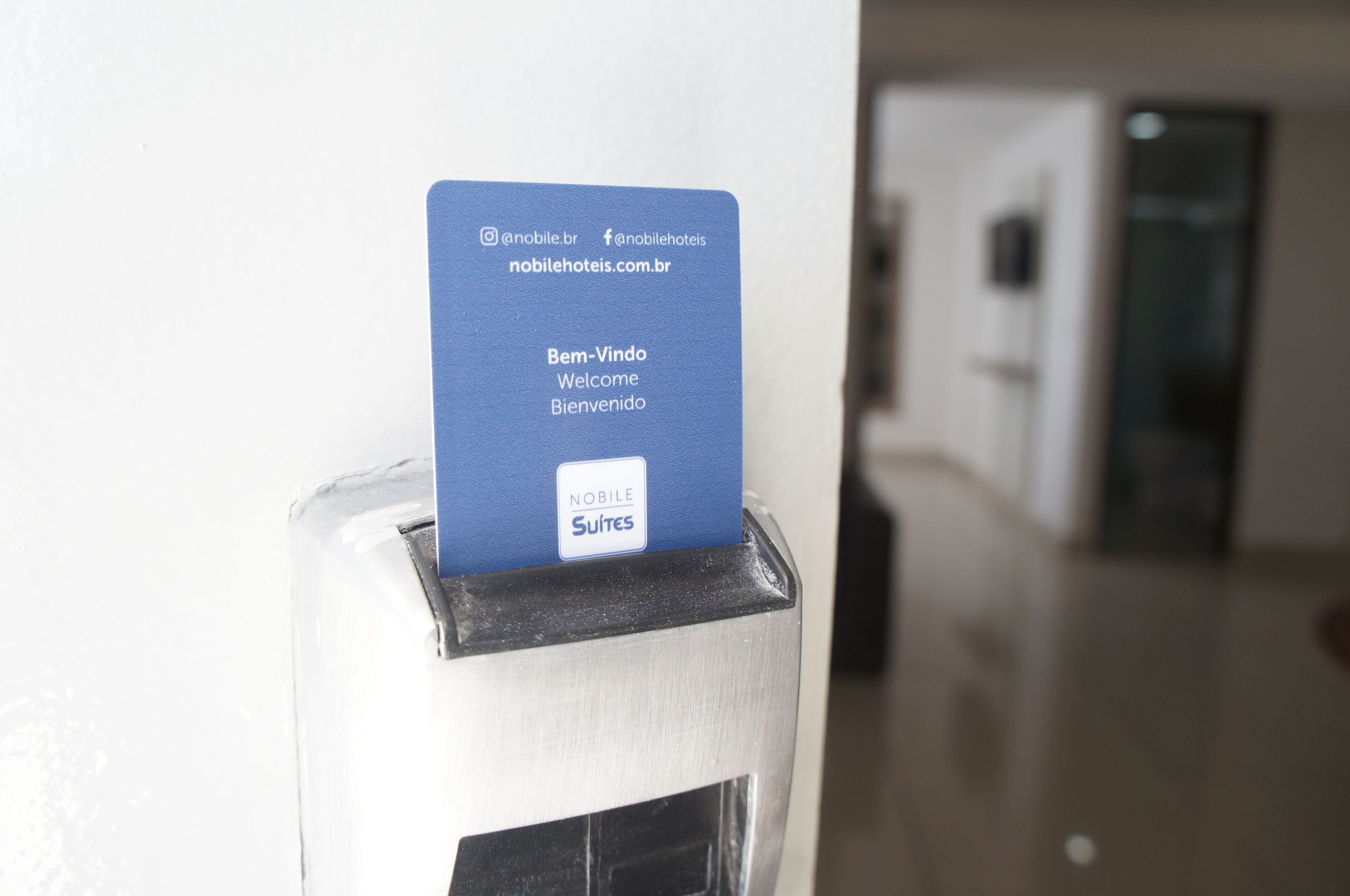 A blue card inserted into a slot on a metallic surface, likely a hotel reception or room entry point.