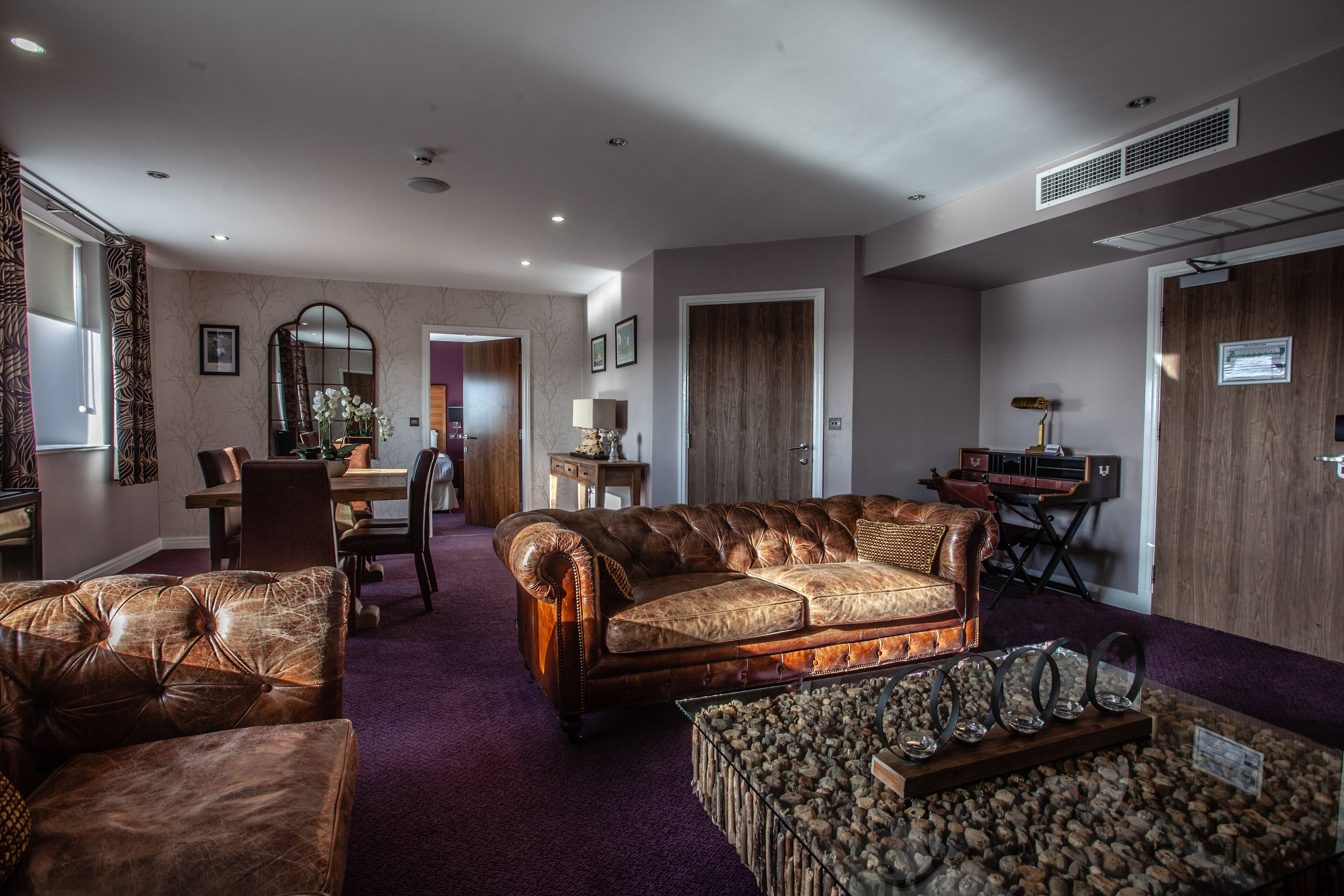 Ein geräumiges Wohnzimmer mit einer Ledersofa, einem Couchtisch und einem Essbereich mit Tisch und Stühlen.