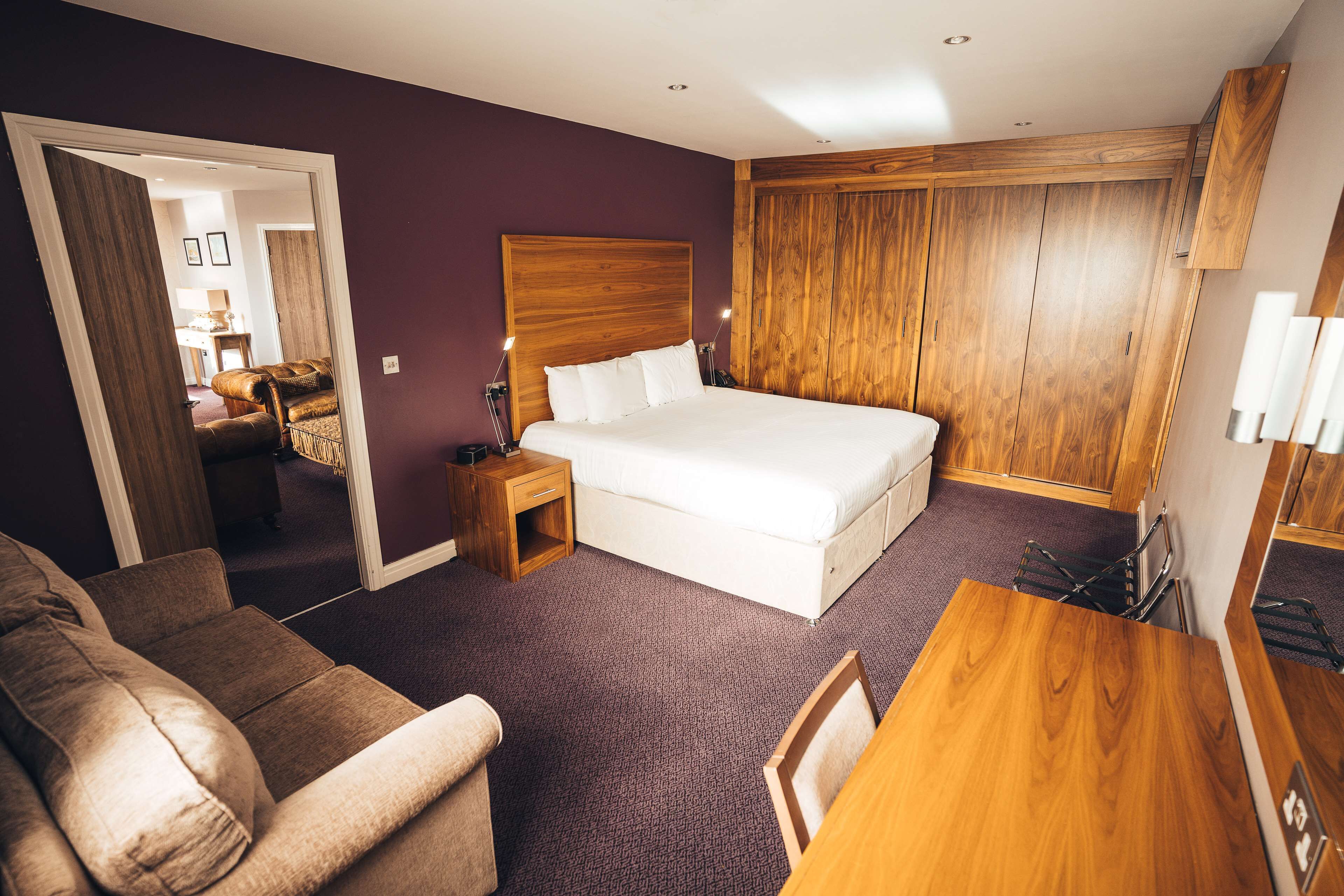 Une chambre d’hôtel avec un grand lit, une armoire en bois, une petite table en bois et un canapé.