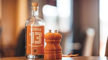 A bottle labeled "The Corner Flag" and two salt and pepper shakers on a wooden table.