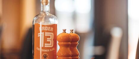 Una botella etiquetada como "The Corner Flag" y dos saleros y pimenteros sobre una mesa de madera.