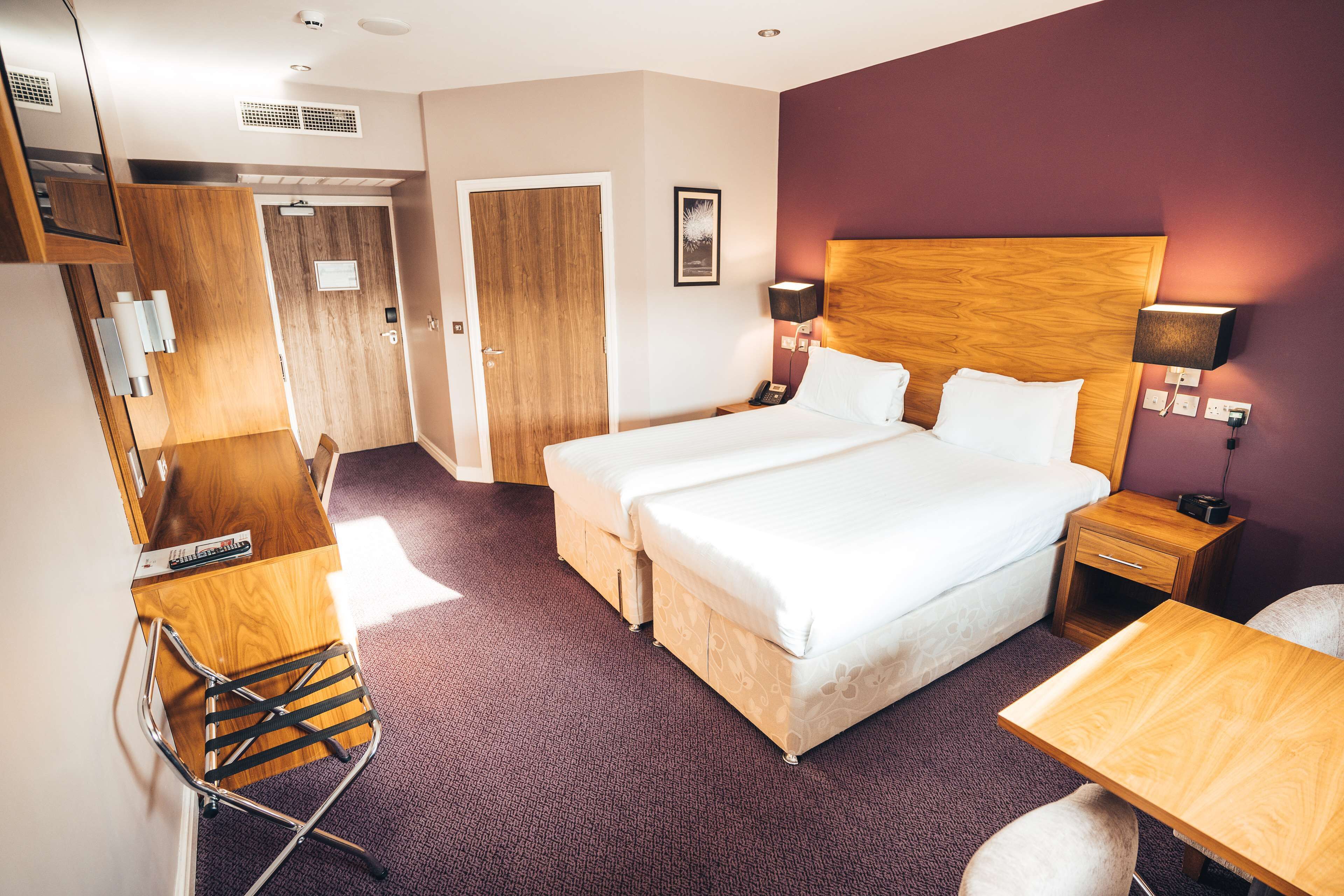 Una habitación de hotel con una cama grande, un escritorio, una silla, un armario y la puerta del baño.