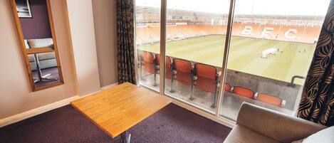 A room with a large window, a wooden table, a couch, and a carpeted floor.