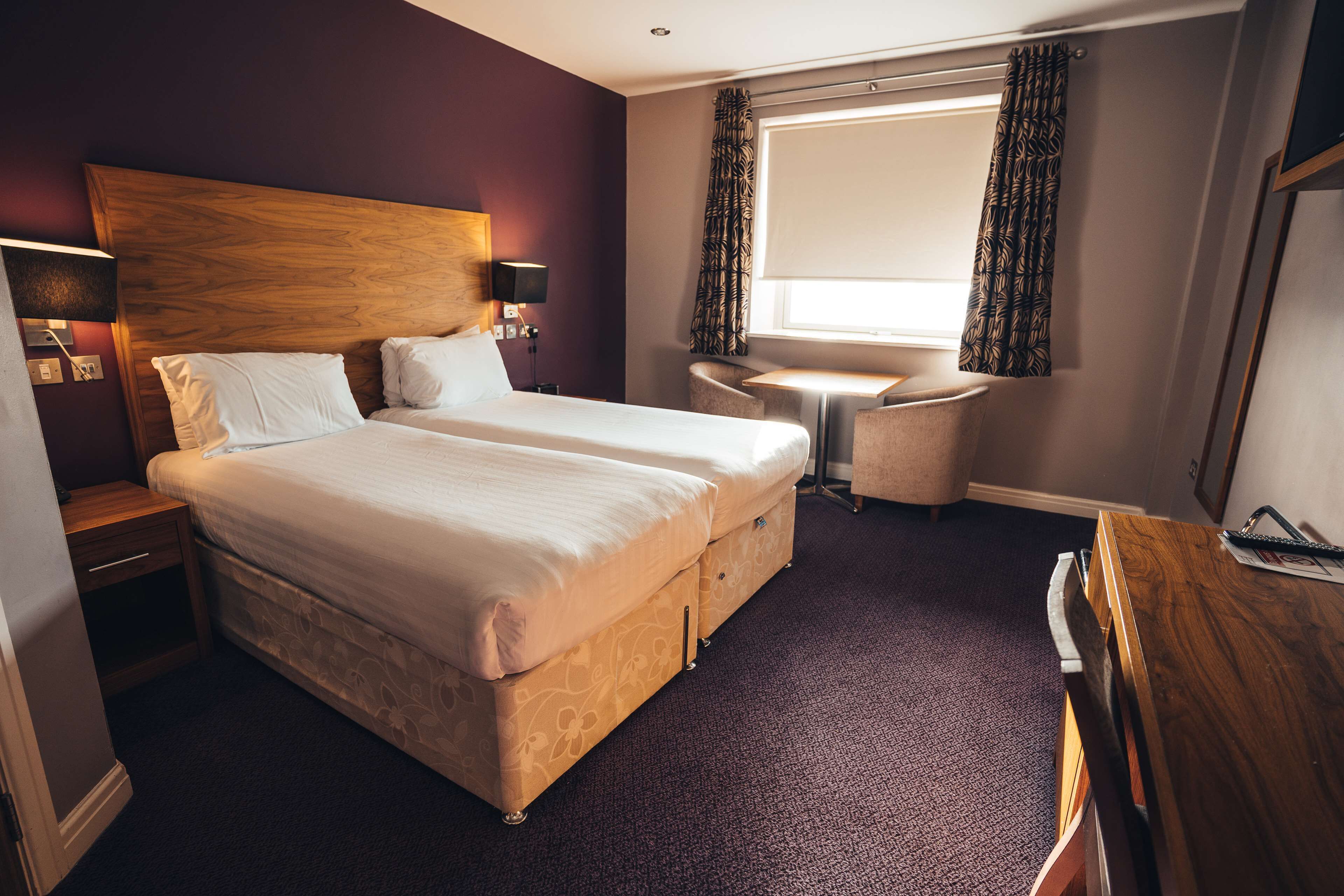 A hotel room with a large bed, bedside tables, a desk, and a chair.