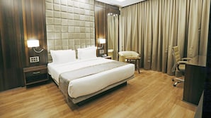 Quarto de hotel com uma cama grande, uma mesa, uma cadeira e um abajur.