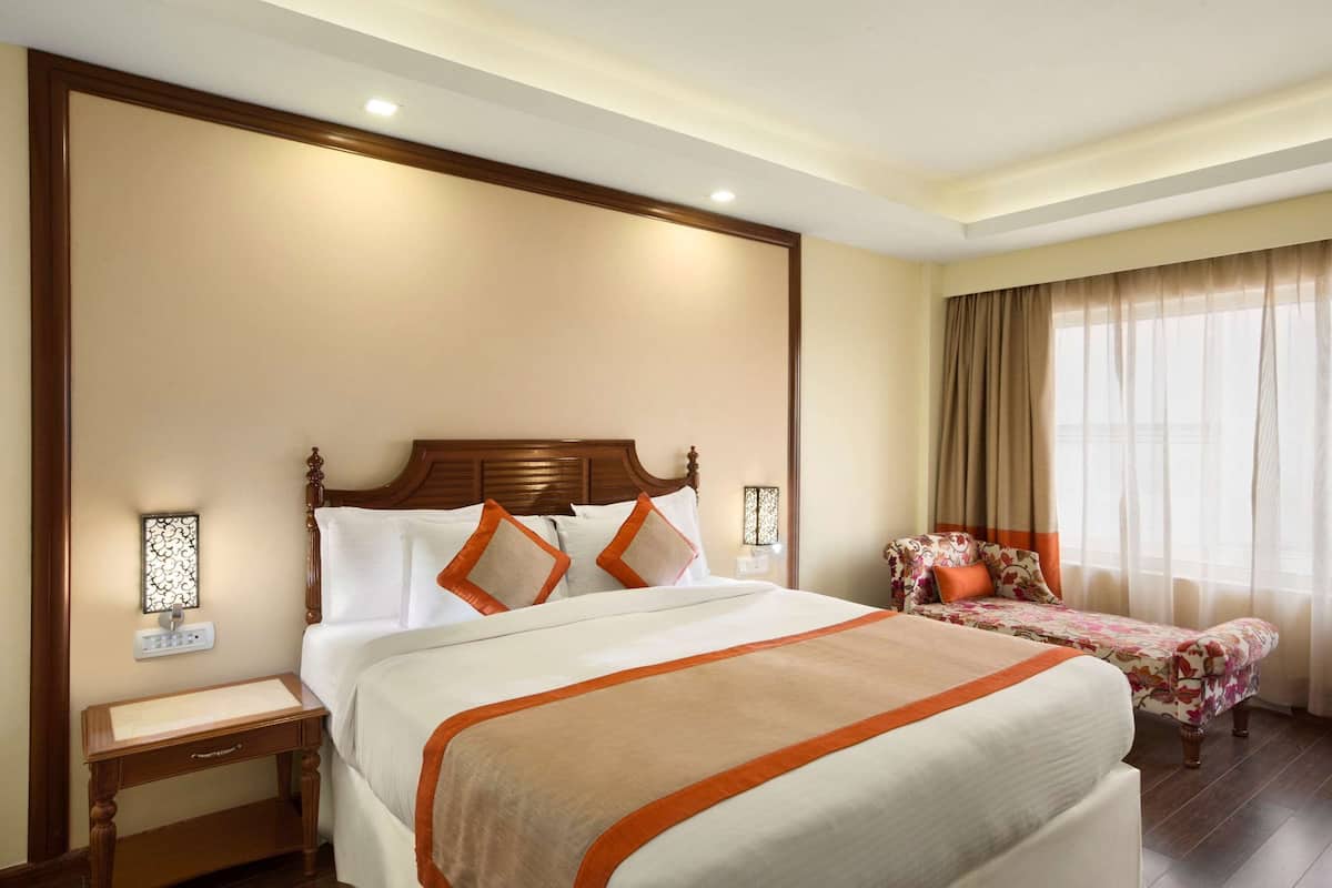 Una habitación de hotel con una cama grande, una mesita de noche, un escritorio y una silla.