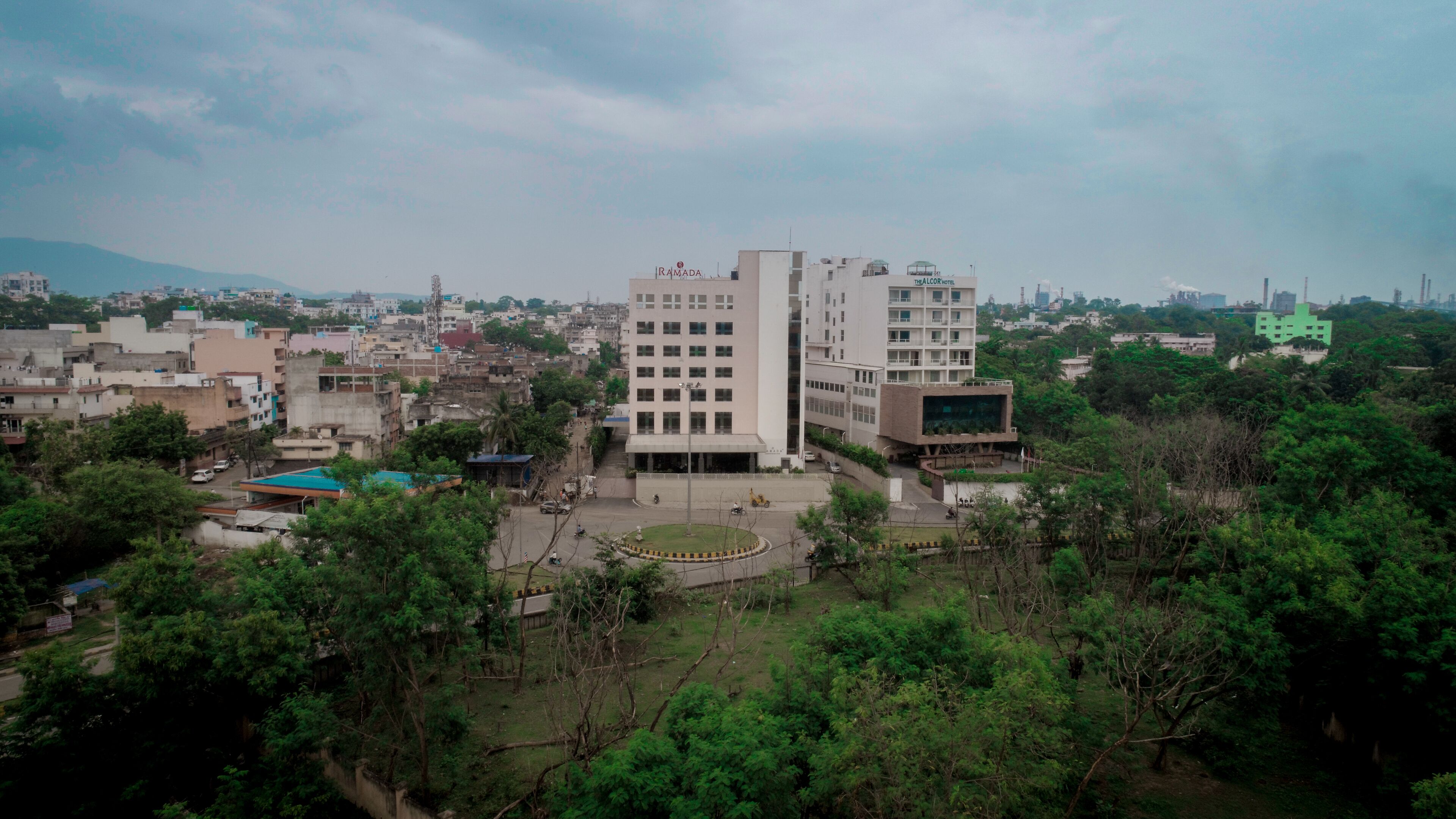 Un edificio de varios pisos con un patio central, rodeado de vegetación y otros edificios.