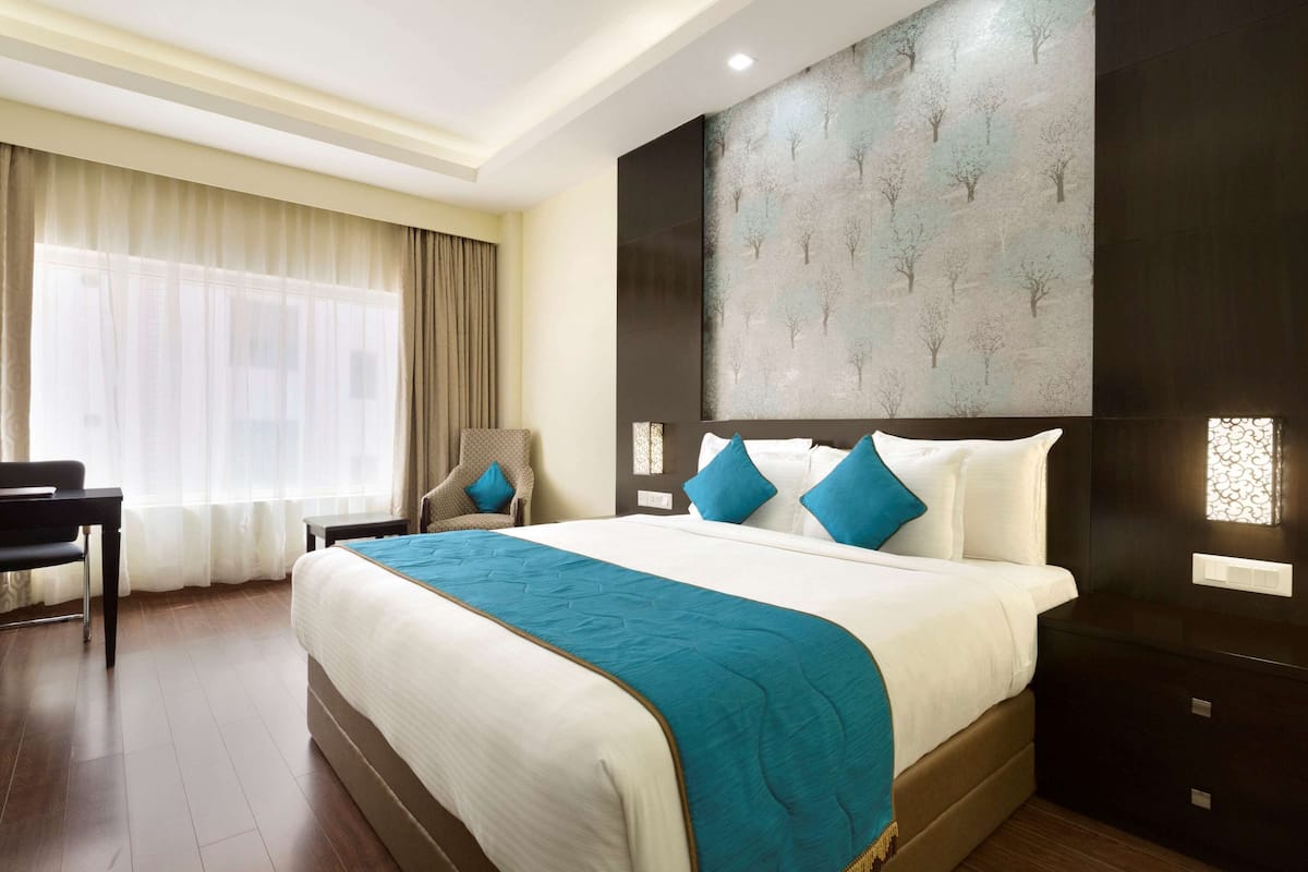 Una habitación de hotel con una cama grande, un escritorio y una silla.