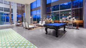 A spacious indoor area with a pool table, comfortable seating, and large windows offering views of the outdoors.
