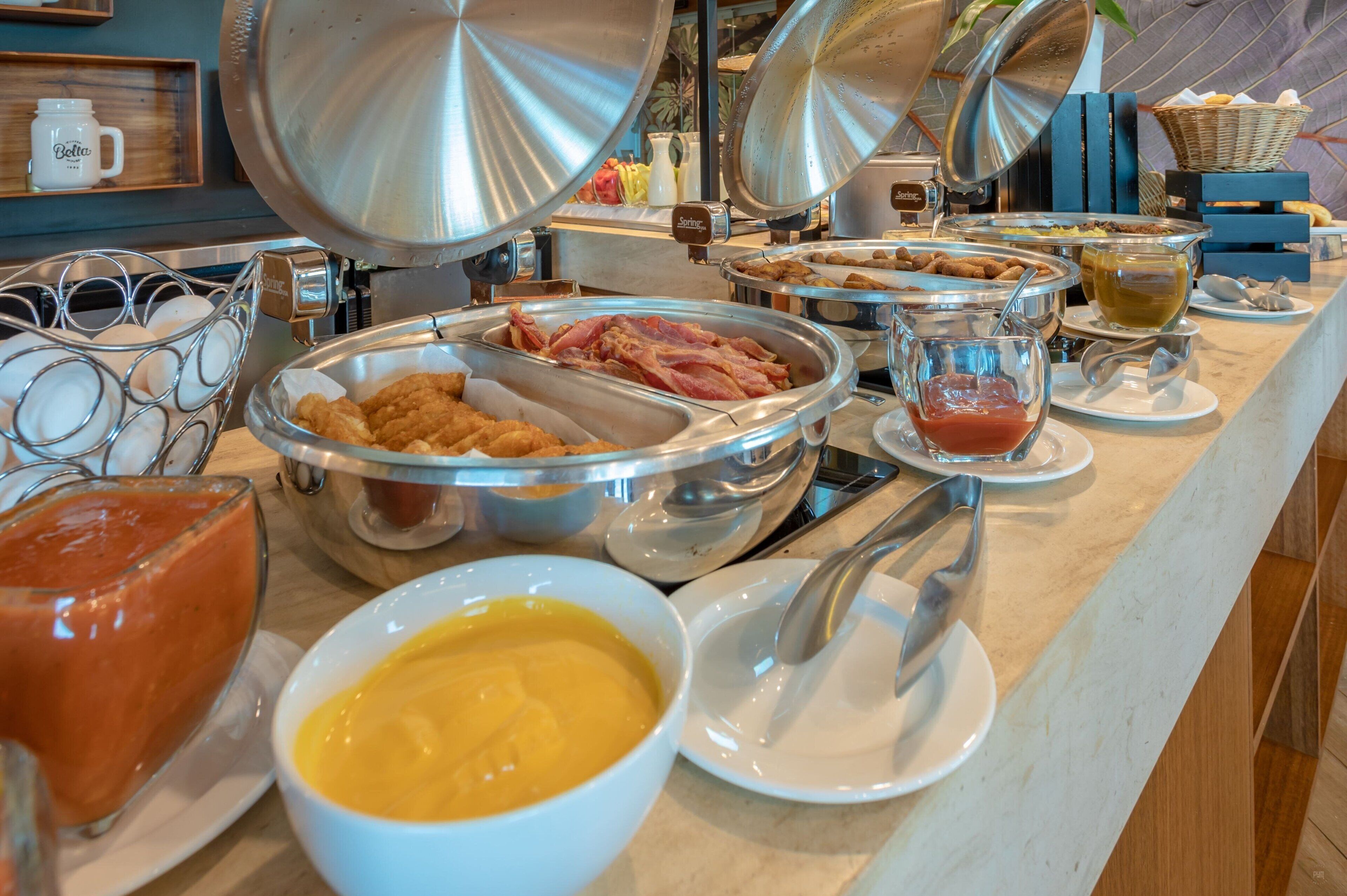 Ein reichhaltiges Buffet mit verschiedenen Speisen, darunter Eier, Speck und verschiedenen Soßen.