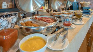 Un bufé con diversos alimentos, como huevos, tocino y diferentes salsas.