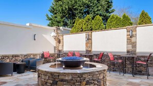 Un patio exterior con muros de piedra, un hogar para fuego y mobiliario de exterior.