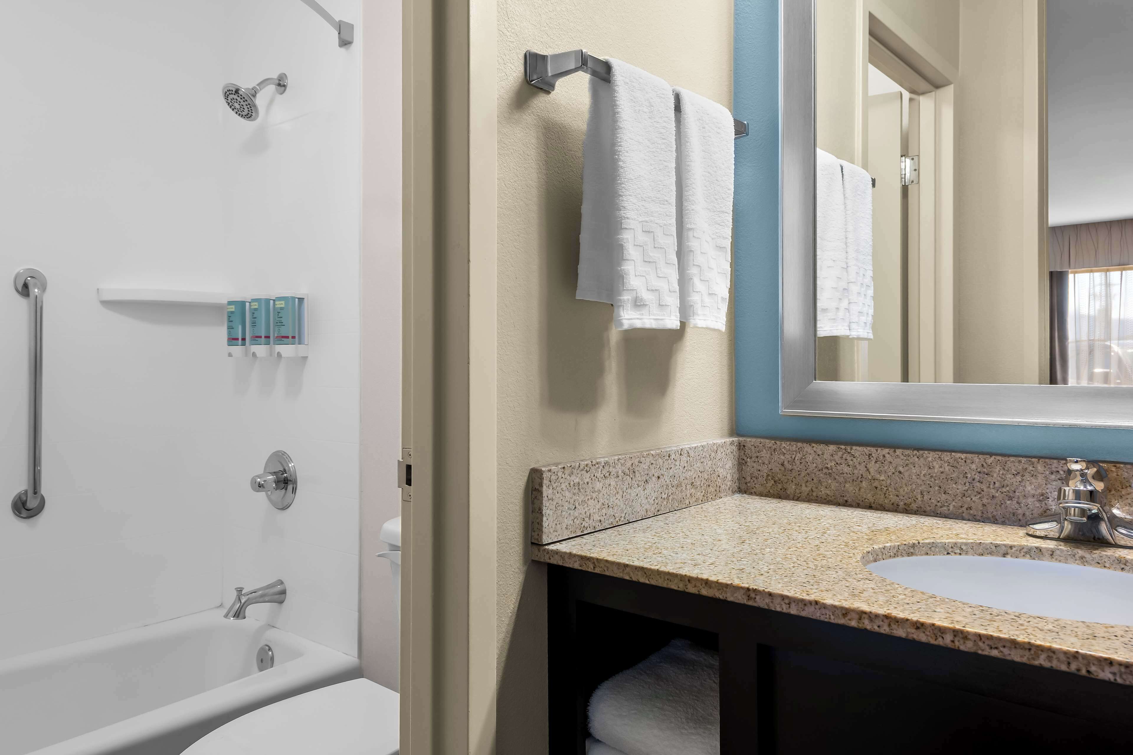 A bathroom with a bathtub, a sink, and a mirror.