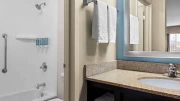 A bathroom with a bathtub, a sink, and a mirror.