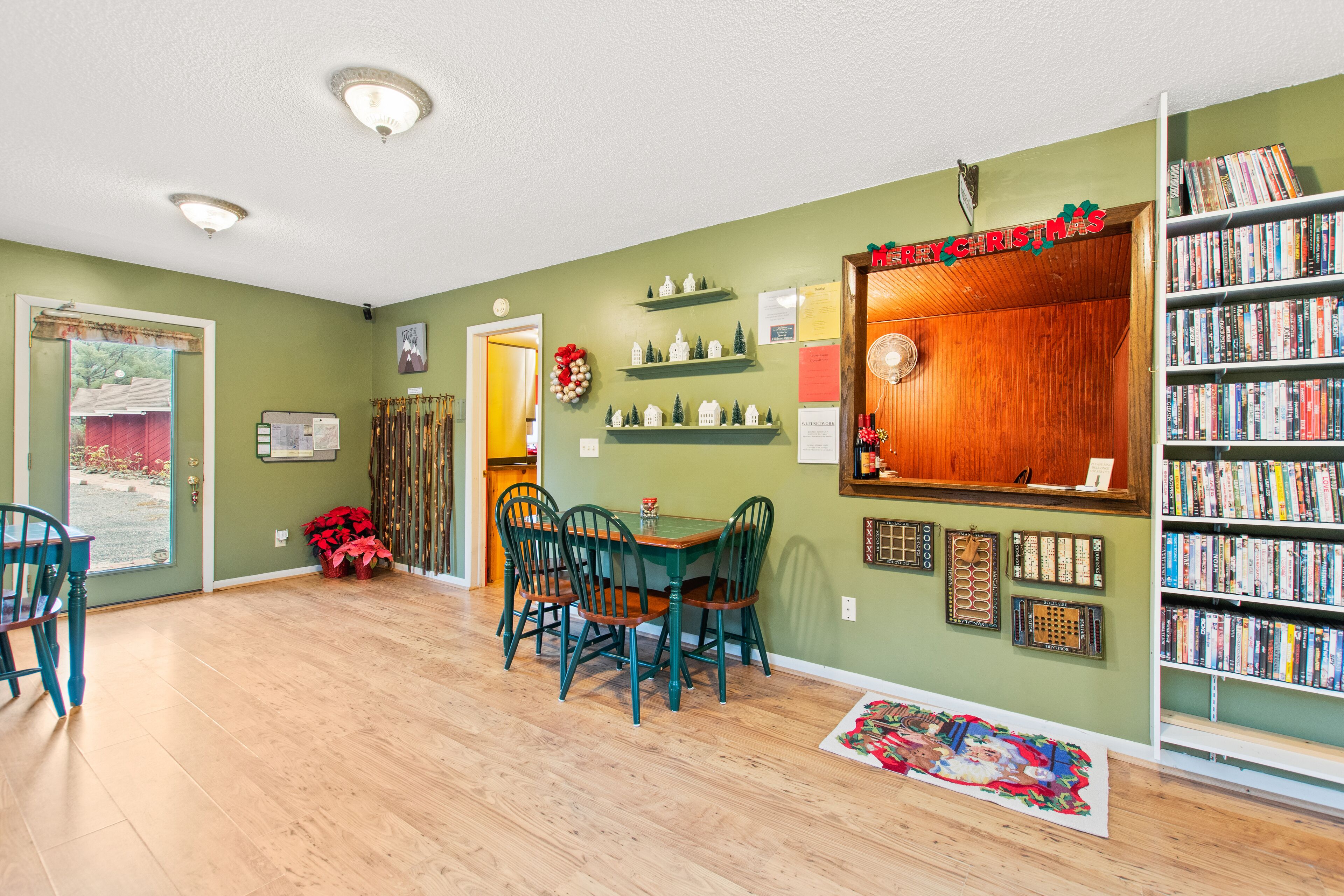 A dining area with a table and chairs, a bookshelf, and a door leading outside.