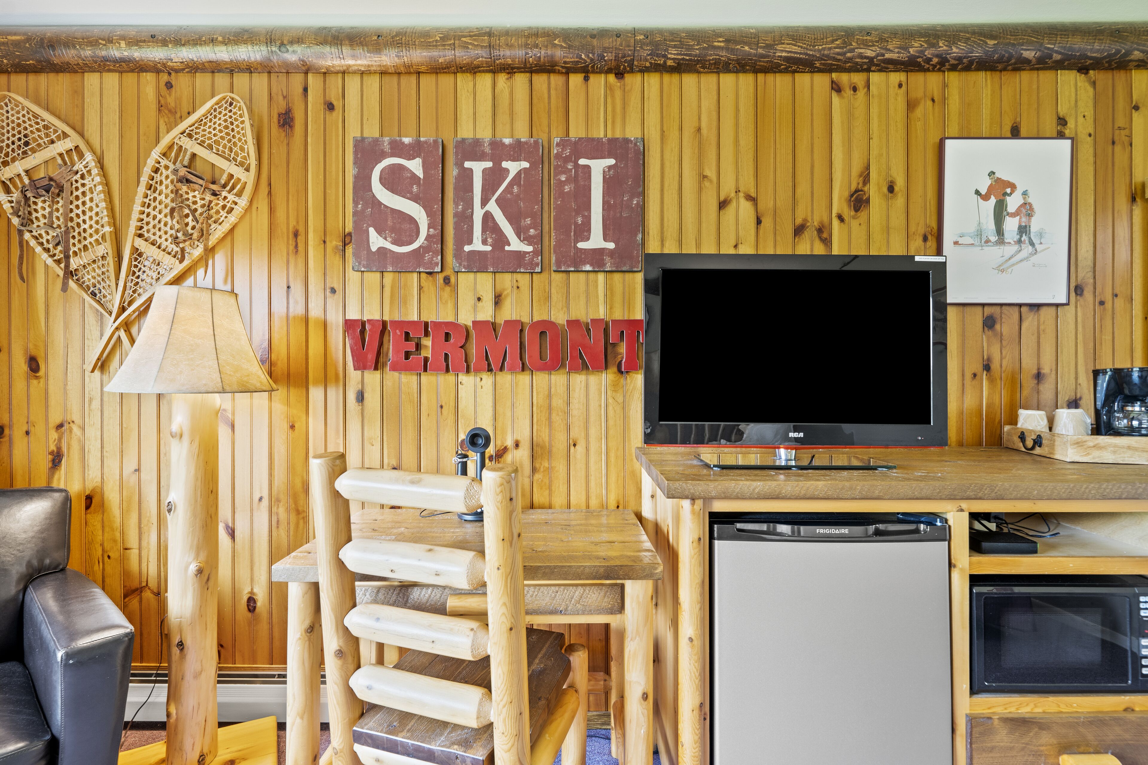 Habitación con temática de esquí, paredes de madera, televisor, refrigerador y microondas.