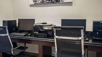 A workspace with three HP desktop computers, a printer, and a black office chair.