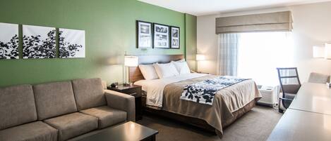 A hotel room with a bed, a sofa, a coffee table, and a desk.