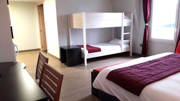 Et hotelværelse med køjesenge, et skrivebord og en stol.