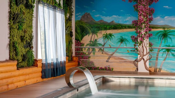A pool with a waterfall feature, surrounded by a tropical mural, and a wooden log bench. - Best Western Hotel & SPA Pau Lescar Aeroport (Lescar)