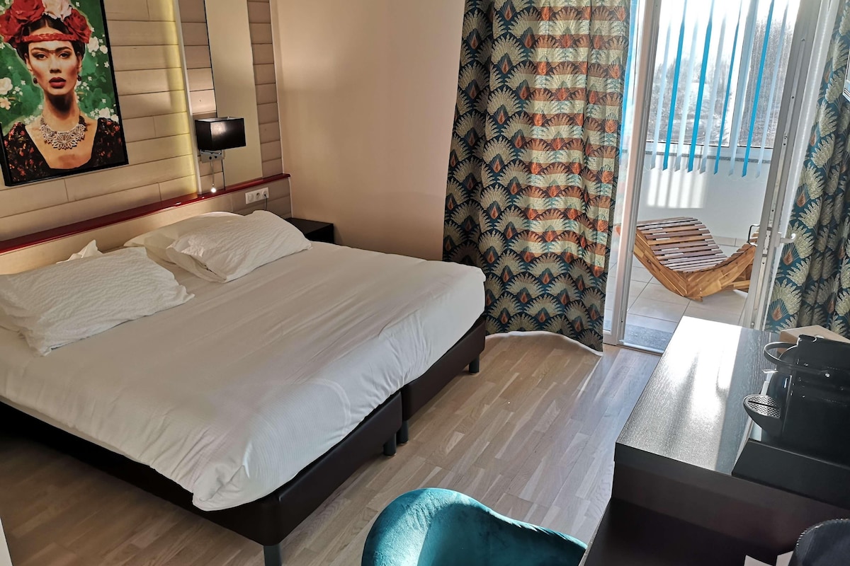 Habitación de hotel con una cama grande, un escritorio, una silla y vistas al exterior.