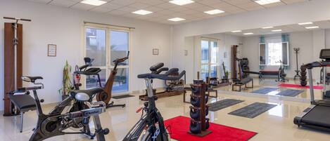 Un gimnasio amplio con diversos equipos de ejercicio, incluyendo bicicletas estáticas, cintas de correr y máquinas de pesas.