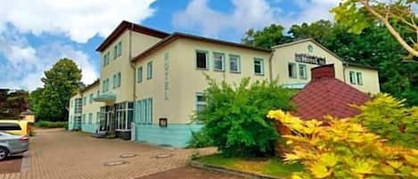 Un hotel con camino de ladrillo y zona ajardinada con follaje amarillo.