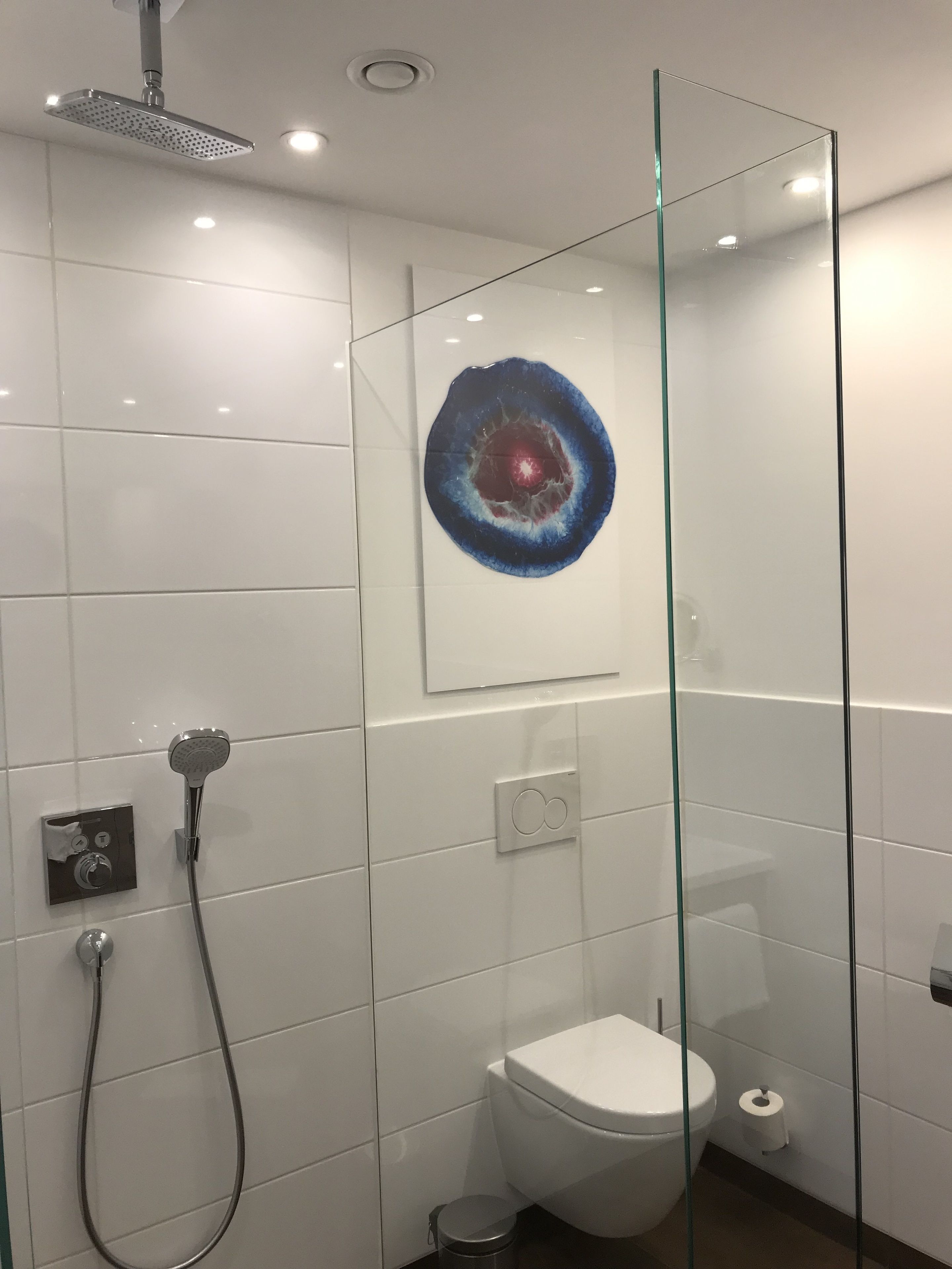 Un baño moderno con cabina de ducha de vidrio, inodoro y lavamanos empotrado.