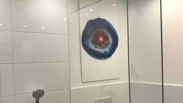 Un baño moderno con cabina de ducha de vidrio, inodoro y lavamanos empotrado.