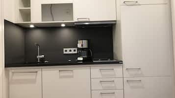 Une cuisine moderne avec des meubles blancs, un plan de travail noir et une machine à café.