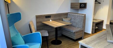 Quarto moderno com uma cadeira azul, uma mesa de madeira e um banco embutido com almofada.