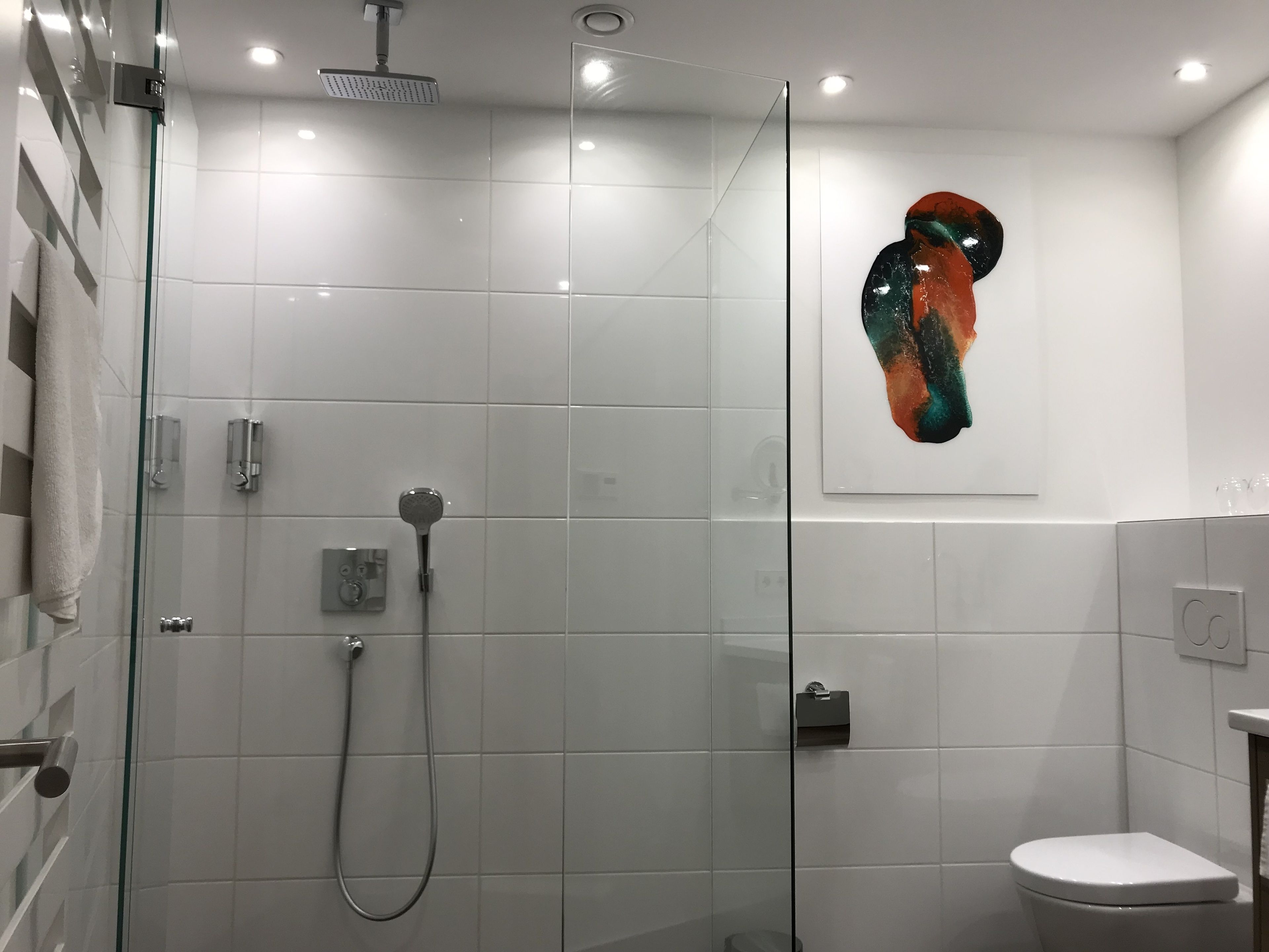 Ein modernes Badezimmer mit einer Duschkabine, einer Toilette und einem wandmontierten Waschbecken.