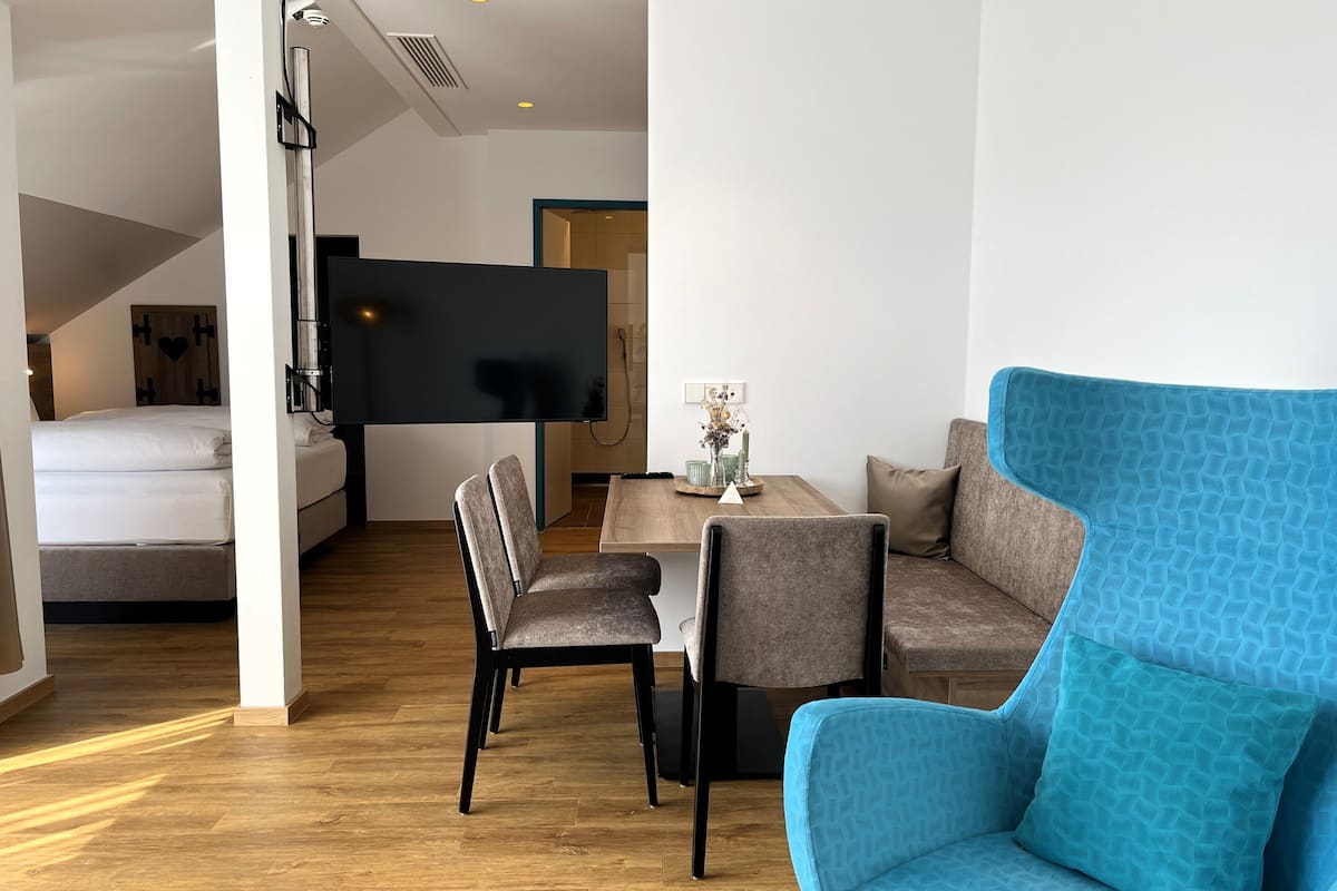 Un salon moderne avec un canapĂ© bleu, une table Ă manger avec des chaises et un lit Ă lâarriĂšre-plan.